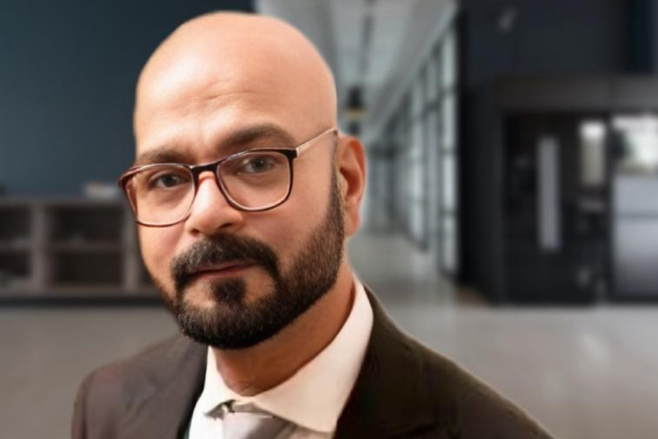 Profile photo of Mazhar Abbasi wearing a suit and tie, with an office space in the background