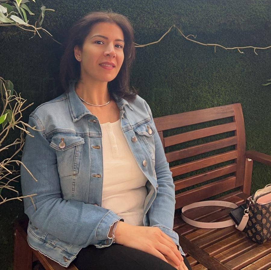 Pathways to Work Bankstown student Hanan, sitting on a wooden bench and facing towards camera