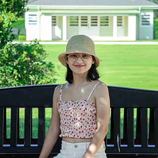 IELTS student Hongyu Meng sitting on a bench in front of grassed area (320x320)