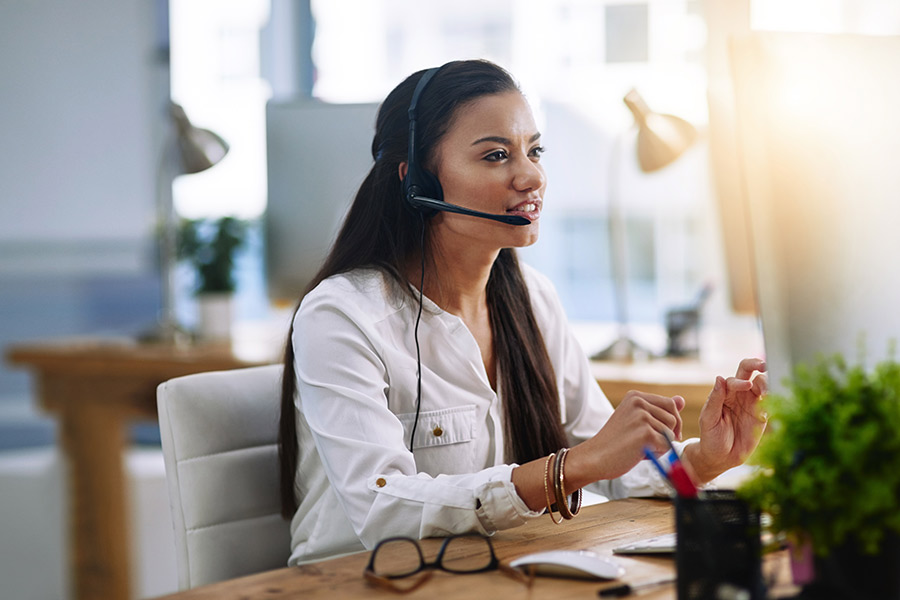 A young student sitting in an office space and wearing a customer service headset (900x600).