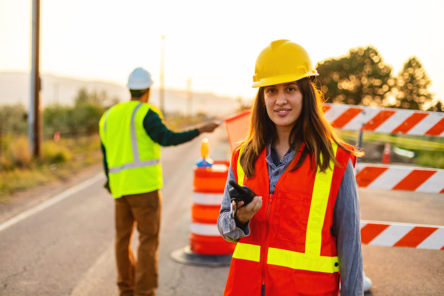 A Skills for Traffic Control short course student standing on a road, wearing a high visibility vest and a yellow hard hat (900x600).