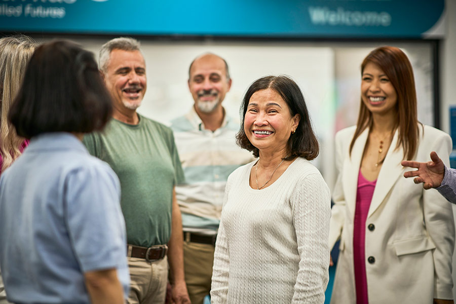 Six NSF Social English short course students standing in a group, with one female student smiling directly towards camera (900x600).