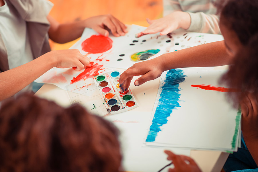 A close up photo of several children's hands doing a finger painting activity (900x600).