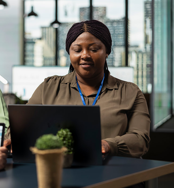 A female employment service provider working from a laptop and wearing a lanyard (740x800).