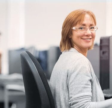 Woman with glasses smiling, facing forward.