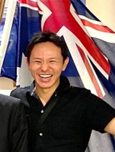 Photo of smiling man in front of Australia flag