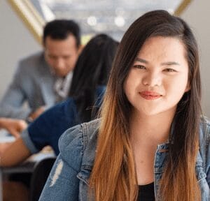 Young adult smiling. People sitting at table in background