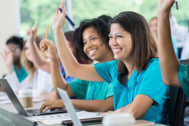 Students in classrooms with hands up