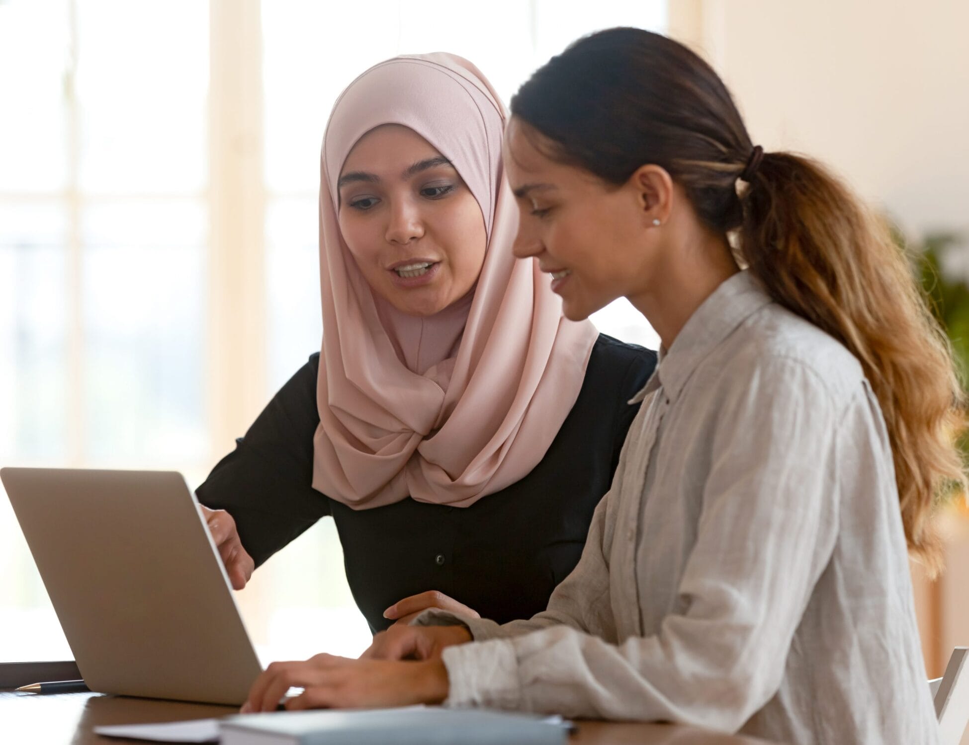 Female teacher wearing headscarf helping student